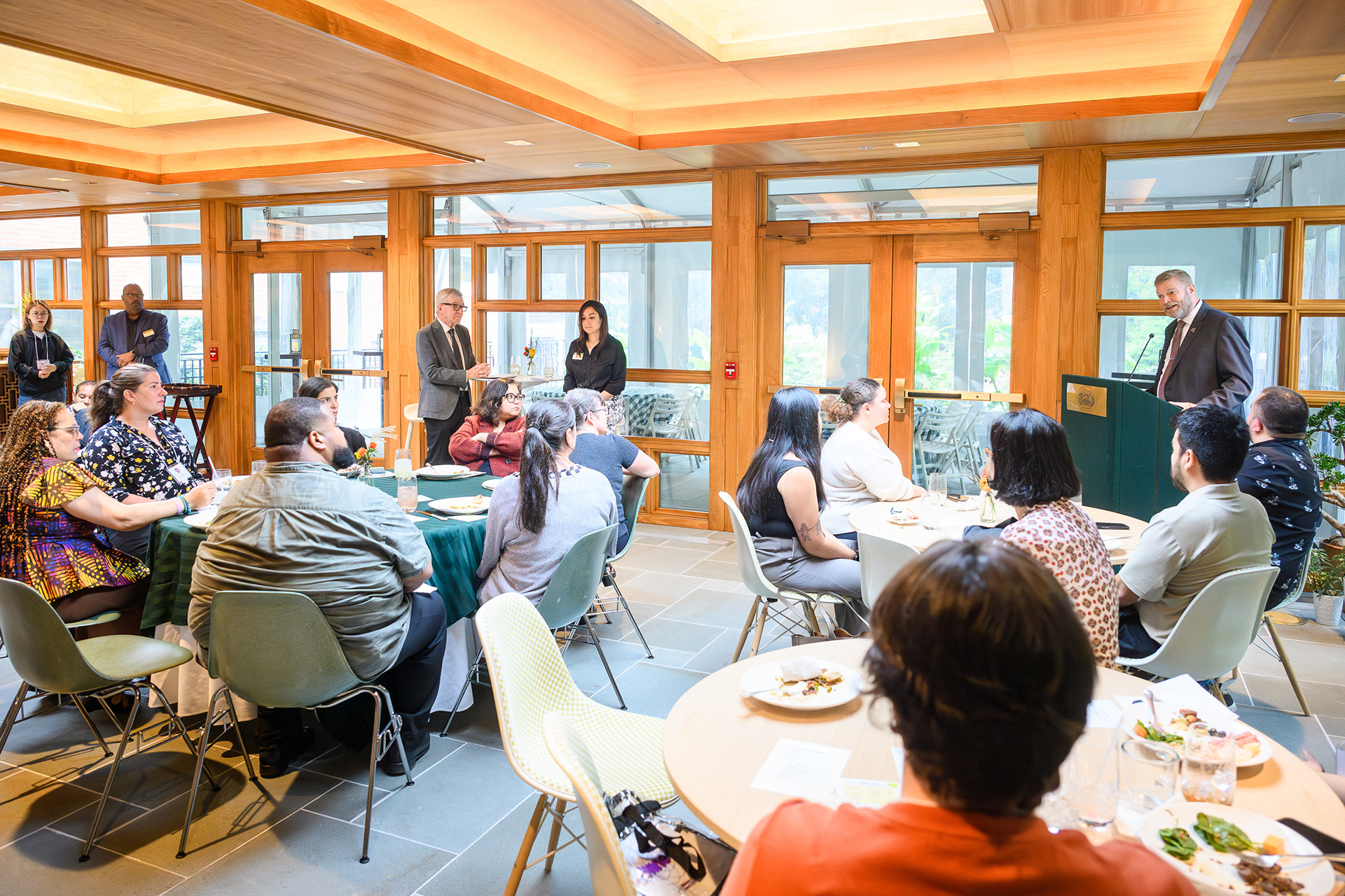 A speaker at the lectern addresses the room of people sitting and standing