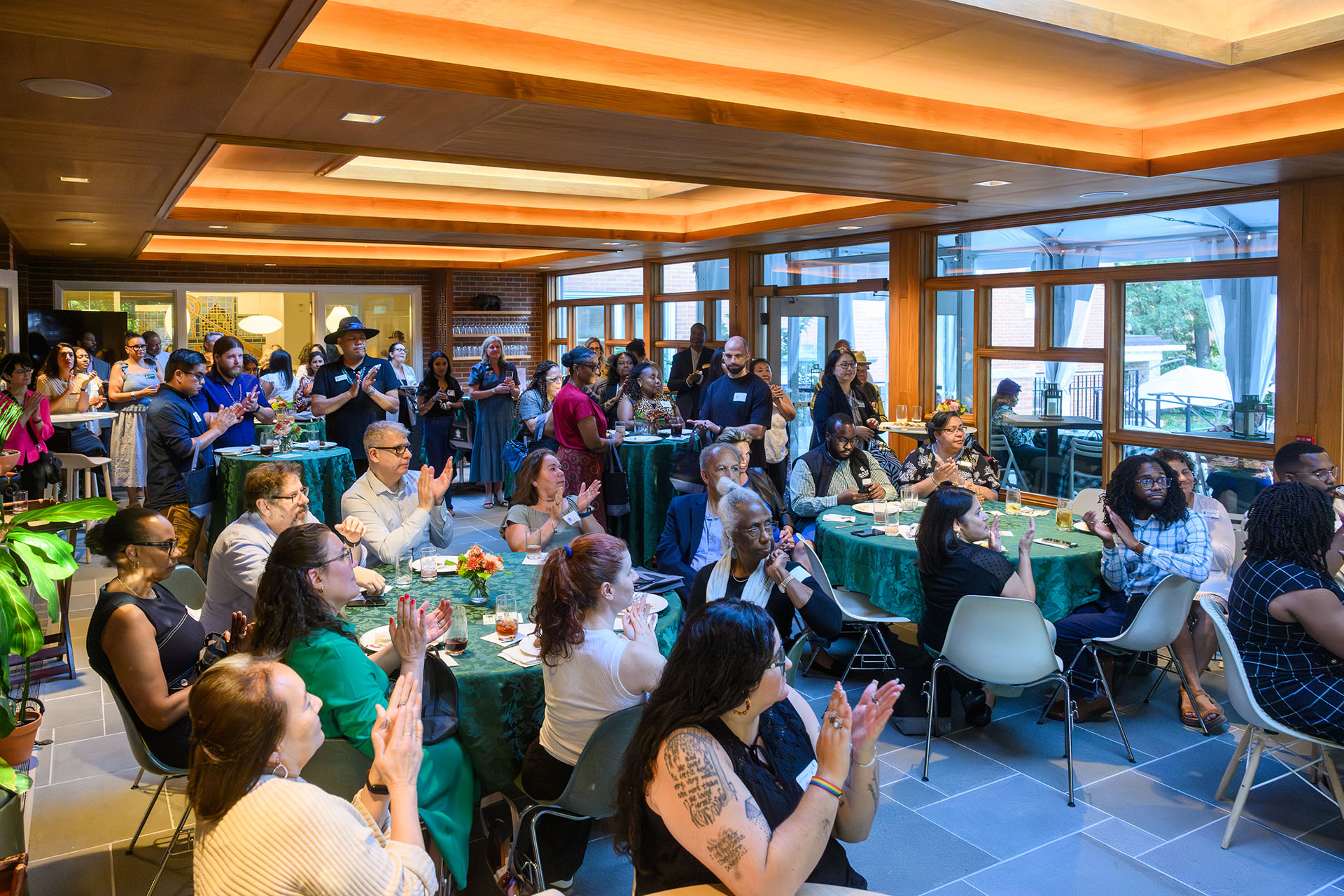 A group os seated and standing people in a room applaud