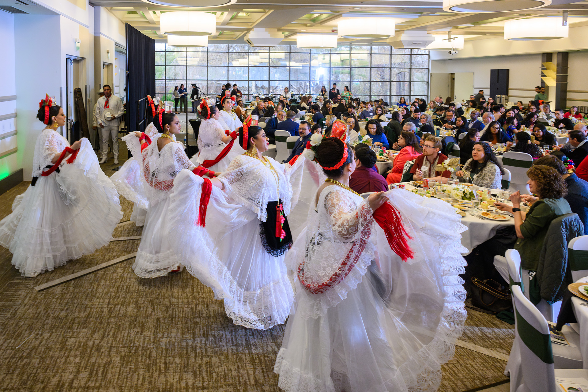 folklore dancers in white flowing dresses face the audience in the background