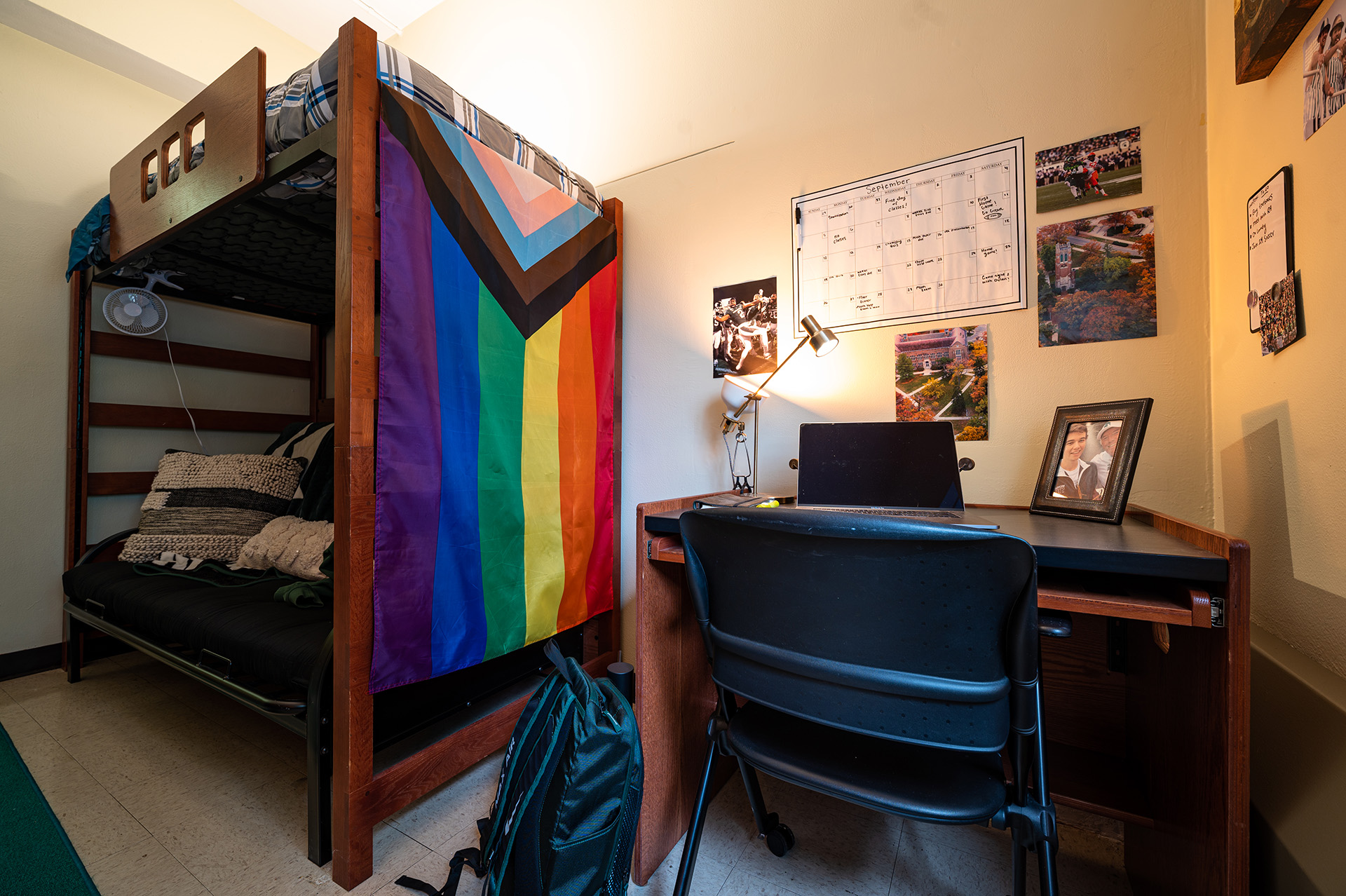 dorm room with a progressive pride flag drapped on the bunk bed frame