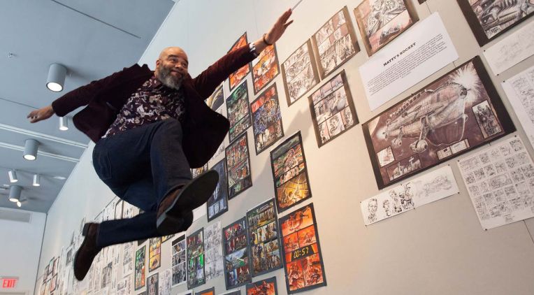 Tim Fielder leaping in the air along a row of comic book shelves